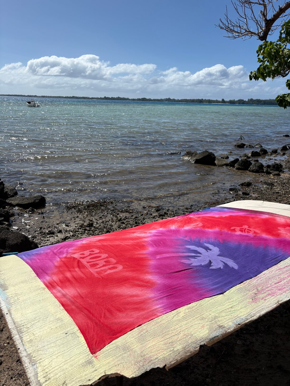 Paréo peint aux couleurs vives étalé sur la plage, photo partagée par Priscilia P.